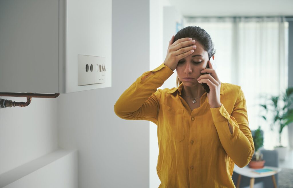 worried woman calling a boiler breakdown service on her phone